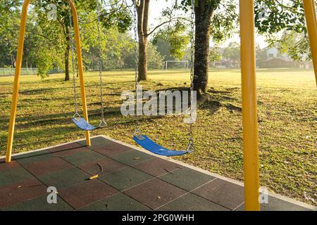 Playground swing set in a public park with lovely morning sunlight. Stock Photo