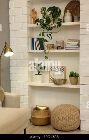 Beautiful green plants and different decor on shelves indoors. Interior design Stock Photo