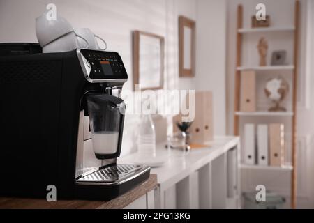 Modern coffee machine on table in office. Space for text Stock Photo