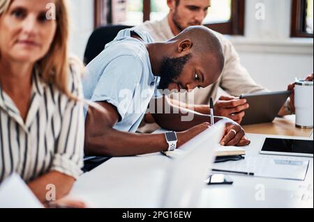 Hes always taking notes. a handsome young businessman taking notes during a meeting in the boardroom. Stock Photo
