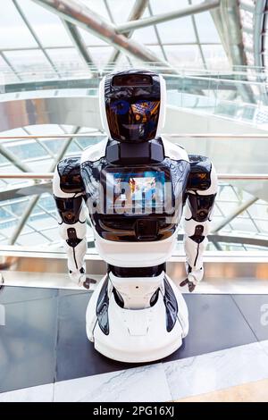 promobot robofoto full length portrait with image of people on display in modern technological interior. smiling face of robot. White android promobot Stock Photo