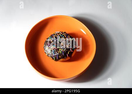 Colourful donut in orange plate on white background. Top view Stock Photo