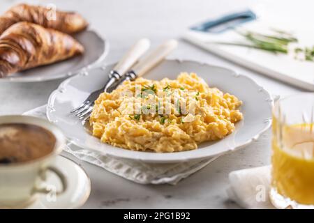 Breakfast served with a plate of scrambled eggs, croissants, orange juice and cofffee. Stock Photo