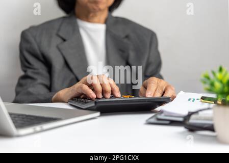 woman using calculator and laptop on desk about cost at home office.Business investment Financing Accounting Banking tax Concept. Stock Photo