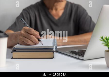 Woman hands with pen writing on notebook in the office.learning, education and work.writes goals, plans, make to do and wish list on desk. Stock Photo