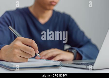 learning online class by using laptop computer and writing notebook at workplace, Education development or knowledge improvement concept. Stock Photo