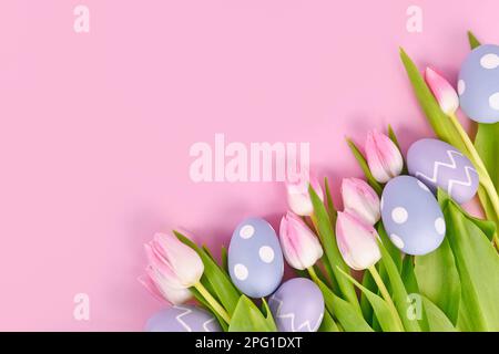 Easter eggs and white tulip spring flowers with pink tips in corner of pink background with copy space Stock Photo
