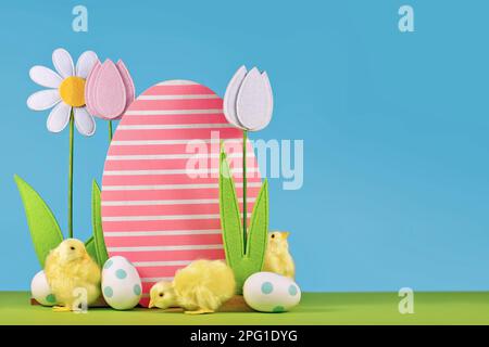 Spring flowers and wooden Easter egg with chicks in front of blue background with copy space Stock Photo