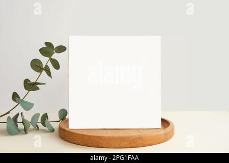 Blank Greeting Card, Invitation Mockup. Front view Eucalyptus Plant, Modern Wooden Plate, Boho Paper Mock Up on Gray Table. Copy Space. Minimal Busine Stock Photo