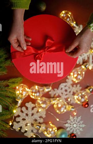 Woman holding christmas gifts laid on wooden table background with christmas decoration Stock Photo