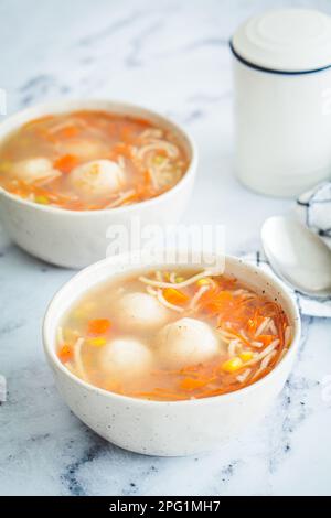 Potato balls soup with noodles and vegetables in a white bowl, white background. Vegan food concept. Stock Photo