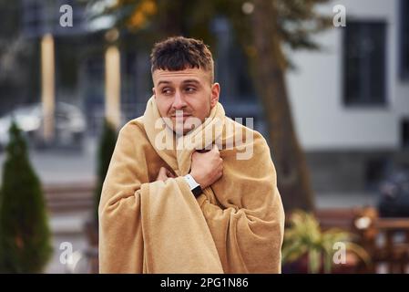 Young man in pajama is outdoors on the street. Feels sleepy Stock Photo