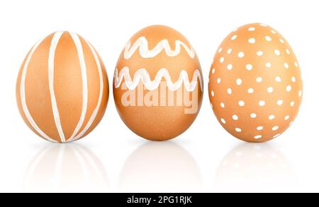 Three Easter brown eggs decorated with patterns of white paint. Natural isolated eggs Stock Photo