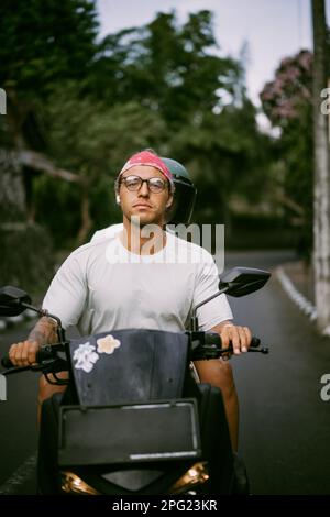 Man in a red bandana rides a bike in Bali. Tropical lifestyle. Stock Photo
