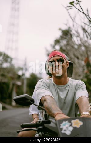 Man in a red bandana rides a bike in Bali. Tropical lifestyle. Stock Photo