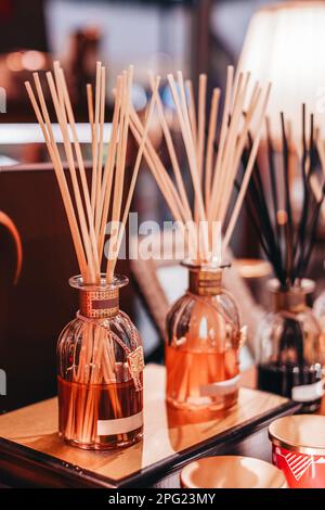 Mockup glass bottle with aroma sticks diffusers on wooden stand in the shopping mall. Home decoration. Air freshener concept. Vertical Stock Photo