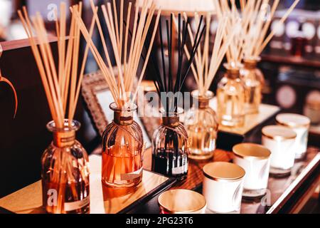 Mockup glass bottles with aroma sticks diffusers on wooden stand in the shopping mall. Home decoration. Air freshener concept. Stock Photo