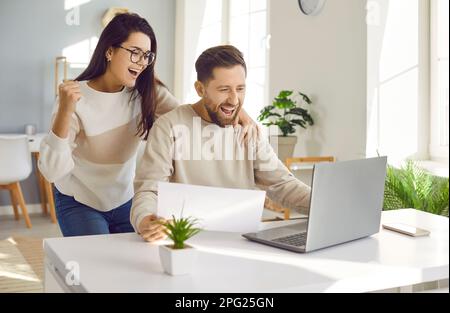 Happy family couple having fun while paying bills and using online banking on laptop Stock Photo
