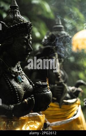 Stone statue of a Hindu god in Balinese Temple, incense smoke. Stock Photo
