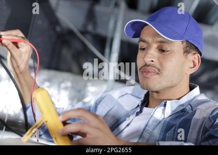 young electrician holds cables in hands and connecting them Stock Photo