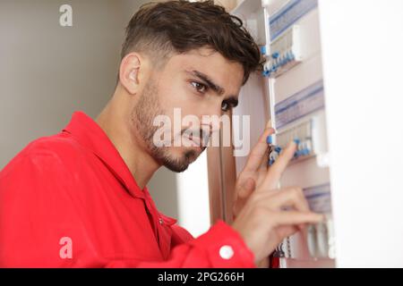 an electrician worker inspecting fuseboard Stock Photo