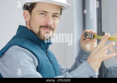 a male builder measuring window Stock Photo