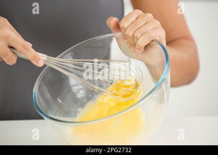 female chef beating eggs with wire whisk in bowl Stock Photo