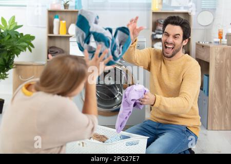 happy couple having fun doing laundry together Stock Photo