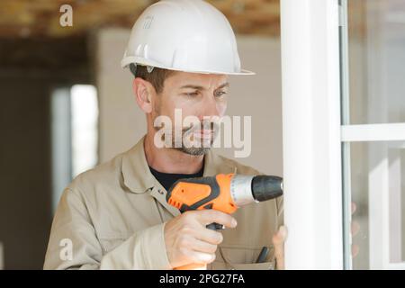 a man drilling a window frame Stock Photo
