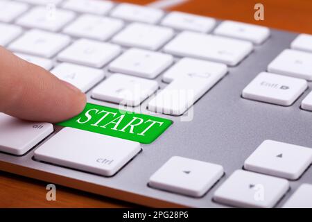 Finger pressing green start button on keyboard. Online begginer succes concept Stock Photo