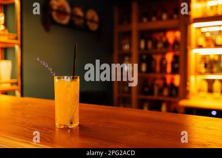 Crystal glass with orange cocktail and sprig of lavender on a bar blurred background. Free space for text. Concept of minimalism Stock Photo