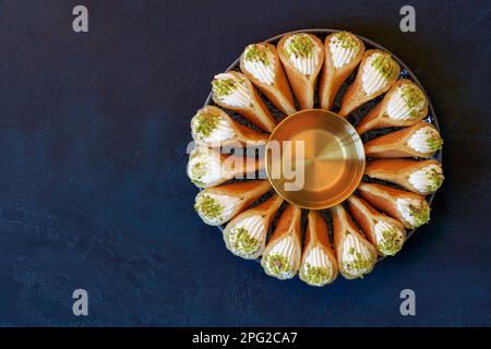 Traditional Ramadan dessert. Arabic cuisine semolina pancakes with cream and pistachio . Qatayef with qishta Stock Photo