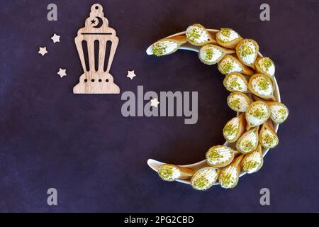 Ramadan kareem with qatayef arranged in shape of crescent moon. Traditional middle estern ramadan sweets. Iftar food concept. Ramadan decor background Stock Photo