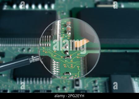 view of printed circuit board with active and passive surface mounted components close up through magnifying glass Stock Photo