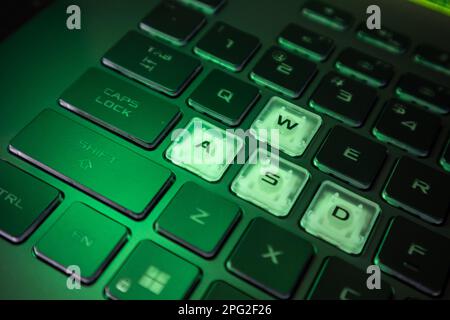 Highlighted gaming keys with green back light and blurred background. Powerful dark notebook keyboard close-up. Tech, IT, e-sport background Stock Photo