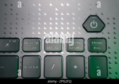 Turn on and off power key in green light. Gaming grey notebook keyboard close-up. Tech, IT, computer science background Stock Photo