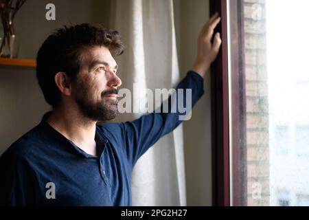 middle-aged man sipping a cup of coffee looking out the window inspired in thoughtful reflection Stock Photo