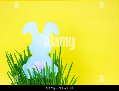 Easter Background with Silhouette bunny in grass on yellow background. Simple easter horizontal background with copy space. Stock Photo