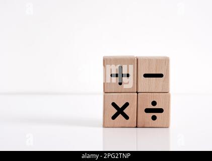 Basic mathematical operations symbols. Plus, minus, multiply and divide symbols on wooden cubes on white background. Mathematic or math education and Stock Photo