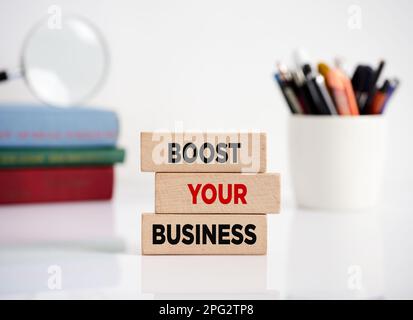 The message boost your business on wooden blocks on an office desk. Business growth, sale or income development and profitability concept. Stock Photo