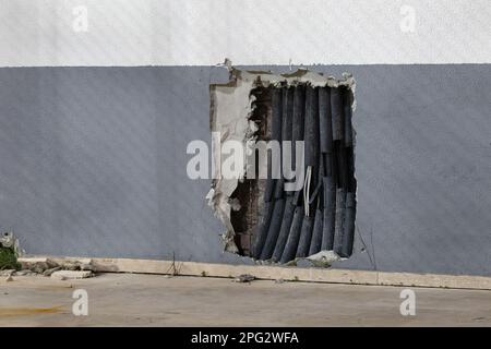 Old electrical wires in damaged plastic insulation, in mounting hole in the wall. Dangerous and bad electrical wiring, troubleshooting in power supply Stock Photo