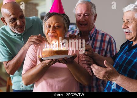 Happy group of diverse senior friends celebrating birthday with cake and presents Stock Photo