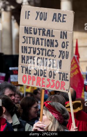 Protest taking place in London on UN Anti Racism Day. Stand up to Racism. Side of the oppressor slogan placard. Desmond Tutu quote Stock Photo