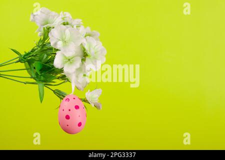 Charming depiction of Easter festivities, showcasing pink egg painted in polka dots and swinging from a branch in full bloom, contrasted against a viv Stock Photo