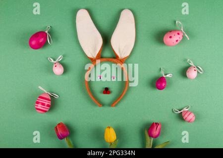 Amusing Easter backdrop in green hues featuring pink eggs and a bunny countenance Stock Photo