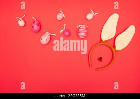 Bunny ears and Easter eggs on a red backdrop with plenty of copy space for Easter greetings Stock Photo
