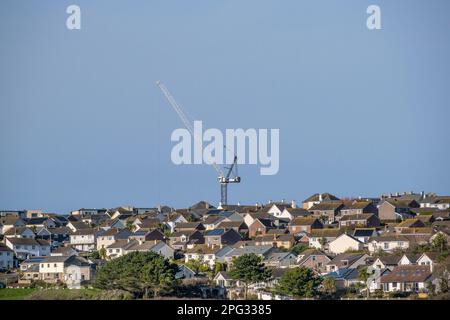A tall crane towering over houses in Newquay in Cornwall in the UK. Stock Photo