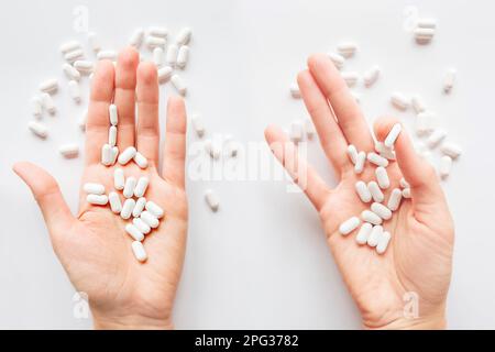 Palm hands full of white scattering pills. Capsules with medicines on light background. Flat lay, top view. Stock Photo