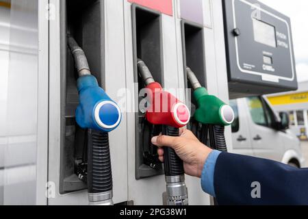 Caucasian man stretching her hand to fuel nozzle with diesel, close up view Stock Photo