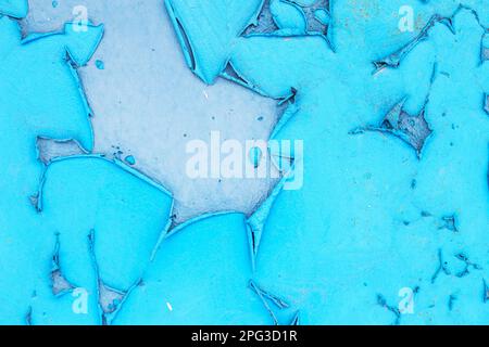 Old blue turquoise paint peeling from concrete or metal wall background. Texture of an old grunge plate with cracked paint with a hole. Stock Photo